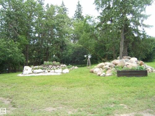 Expansive green lawn with established trees creating a natural backdrop - 543016 Rng Rd 122, Rural Two Hills County, AB - Outdoor