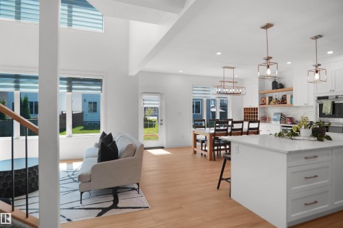 Open-concept living space featuring high ceilings, wood-finish flooring, and white walls - 5802 Soleil Boulevard, Beaumont, AB 