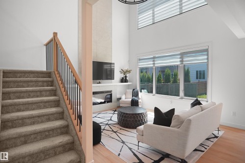 Two-story living area featuring a prominent staircase with wood railing and black spindles - 5802 Soleil Boulevard, Beaumont, AB 