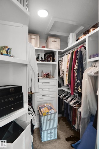 Walk-in closet featuring white built-in shelving, integrated drawers with horizontal pull hardware, ample hanging space, and recessed ceiling lighting - 5802 Soleil Boulevard, Beaumont, AB 