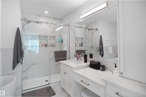 Modern bathroom featuring a glass-enclosed shower with white marble-look tile surround and a recessed niche - 5802 Soleil Boulevard, Beaumont, AB 