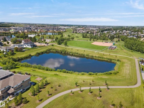Aerial perspective showcasing a residential community with multiple homes and a prominent central pond - 5802 Soleil Boulevard, Beaumont, AB 