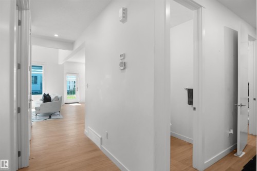 Light wood-finish flooring throughout the hallway and living area - 5802 Soleil Boulevard, Beaumont, AB 