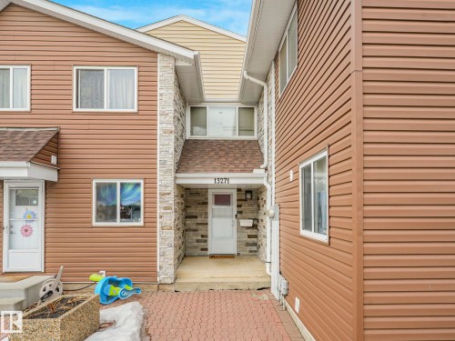 Entrance to property featuring stone siding and a shingled roof - 13271 47 Street Nw, Edmonton, AB 