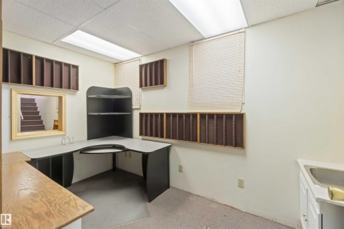 Dedicated workspace featuring a built-in corner desk with shelving, custom wall-mounted organizers, and a window with blinds - 13156 101 St Nw, Edmonton, AB 