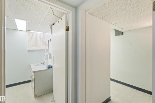 Bathroom featuring a white vanity with an integrated sink, a window with horizontal blinds, and a drop ceiling - 13156 101 St Nw, Edmonton, AB 