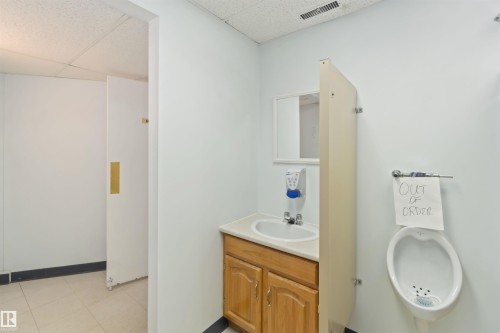 Restroom featuring a wall-mounted urinal, a vanity with a drop-in sink, and a mirror - 13156 101 St Nw, Edmonton, AB 