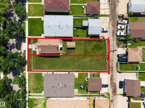 Aerial perspective showcasing a single-family home with a brown shingle roof and white siding, situated on a substantial grassy lot - 13156 101 St Nw, Edmonton, AB 