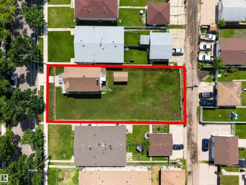 Expansive property featuring a detached residence with a brown shingle roof, a large green lawn, and a small accessory structure - 13156 101 St Nw, Edmonton, AB 