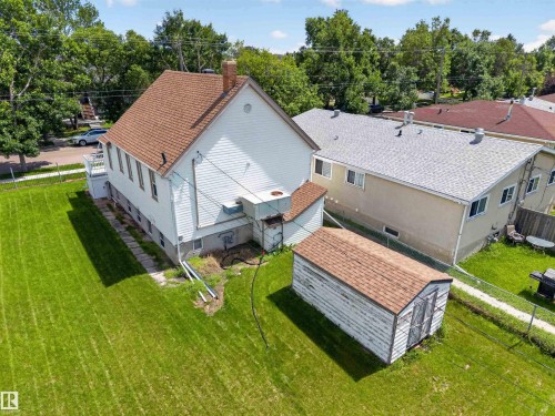 Expansive grassy yard featuring a detached storage shed with a shingled roof, bordered by a chain-link fence - 13156 101 St Nw, Edmonton, AB 