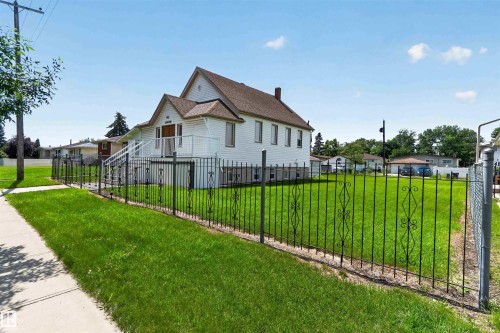 White exterior structure featuring a gabled roof, multiple windows, and a raised entry with steps - 13156 101 St Nw, Edmonton, AB 