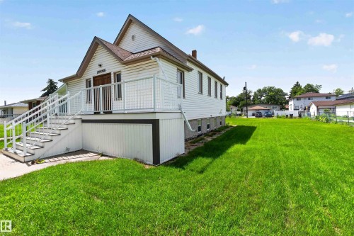 White siding exterior featuring a prominent elevated deck with white railings and exterior stairs - 13156 101 St Nw, Edmonton, AB 