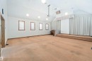 Spacious room featuring vaulted ceilings with pendant and recessed lighting, multiple windows with blinds, an elevated platform, and full-wall drapes - 13156 101 St Nw, Edmonton, AB 