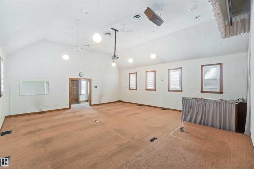 Spacious room featuring vaulted ceilings, recessed lighting, multiple windows with natural wood trim, and wall-mounted speakers - 13156 101 St Nw, Edmonton, AB 