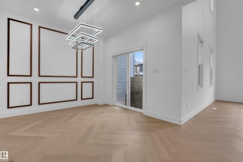 Light wood-finish herringbone flooring spans this bright room, complemented by a contemporary multi-tiered chandelier - 3604 44 Avenue, Beaumont, AB - Indoor Photo Showing Other Room