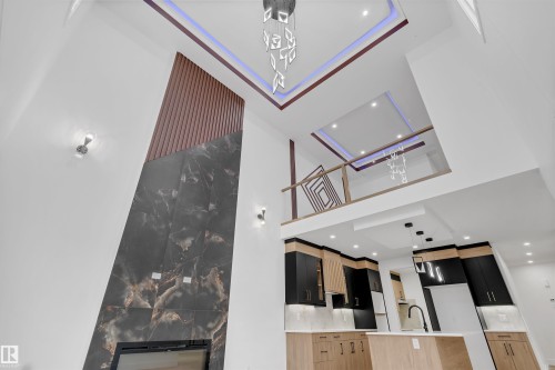 Dramatic two-story living area featuring a black-marbled fireplace with geometric wood paneling - 3604 44 Avenue, Beaumont, AB - Indoor Photo Showing Other Room