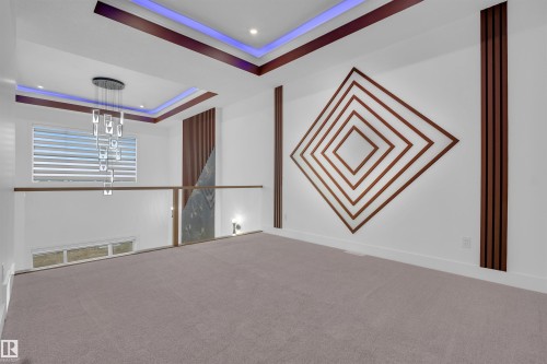Loft area featuring detailed wall paneling, a contemporary chandelier, recessed ceiling lighting with accent illumination, a glass railing, and neutral carpeting - 3604 44 Avenue, Beaumont, AB - Indoor Photo Showing Other Room