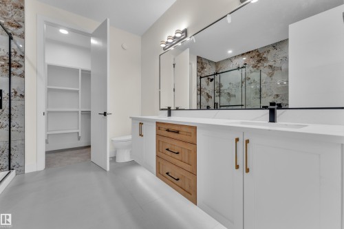 Double vanity featuring white cabinetry, a central wood-finish drawer stack, and gold-tone hardware - 3604 44 Avenue, Beaumont, AB - Indoor