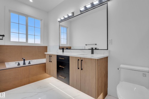 Bathroom featuring a built-in tub with matte black fixtures, a wood-finish tub surround, and a white grid window - 3604 44 Avenue, Beaumont, AB - Indoor Photo Showing Bathroom