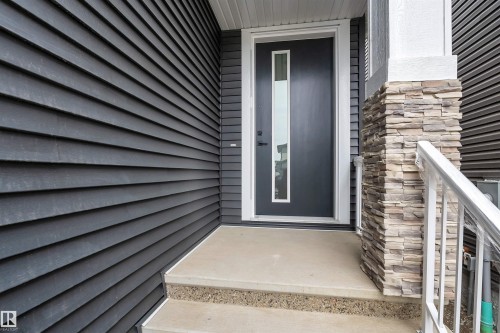 Modern dark gray entry door with vertical frosted glass panel, flanked by dark horizontal siding - 3604 44 Avenue, Beaumont, AB - Outdoor With Exterior