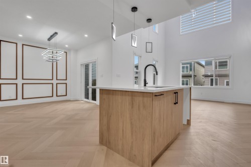 Kitchen island featuring a light wood-finish base, white countertop, and black fixtures - 3604 44 Avenue, Beaumont, AB - Indoor