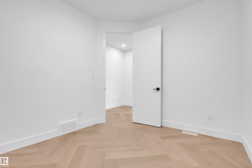Room featuring light wood-finish herringbone flooring, crisp white walls, recessed lighting, and a contemporary white door with matte black hardware - 3604 44 Avenue, Beaumont, AB - Indoor Photo Showing Other Room