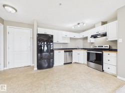 Kitchen featuring light-toned flooring, white cabinetry, dark countertops, a stainless steel dishwasher, and a black refrigerator - 