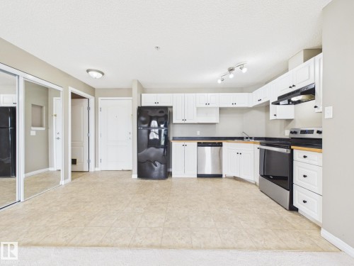 Kitchen area featuring white cabinetry, dark countertops, and tile flooring - #309 5350 199 St Nw, Edmonton, AB 