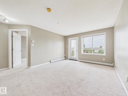 Spacious living area featuring light-toned carpeting, neutral wall paint, and a textured ceiling - 