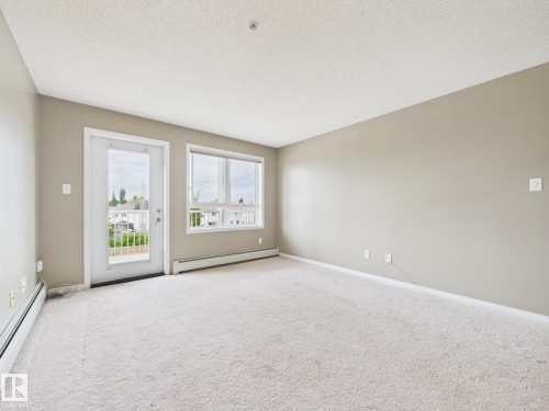 Carpeted interior space with a door leading to an exterior balcony - #309 5350 199 St Nw, Edmonton, AB 