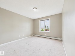 Neutral-toned interior featuring wall-to-wall carpeting, a large window with white trim, and baseboard heating - 