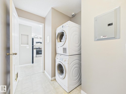 Dedicated laundry area featuring stacked front-loading appliances - #309 5350 199 St Nw, Edmonton, AB 