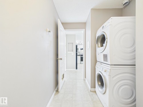 Dedicated laundry area featuring stacked appliances and tile flooring - #309 5350 199 St Nw, Edmonton, AB 