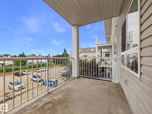 Private balcony with a concrete floor, white railing, and a textured ceiling - #309 5350 199 St Nw, Edmonton, AB 