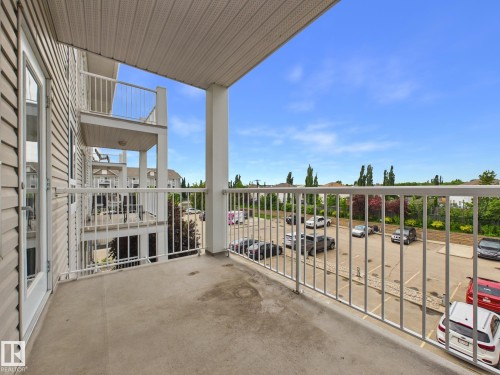 Private balcony featuring concrete flooring, white metal railings, and a sliding glass door entry - #309 5350 199 St Nw, Edmonton, AB 