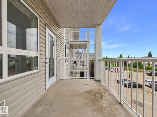 Private concrete balcony with white metal railing - #309 5350 199 St Nw, Edmonton, AB 