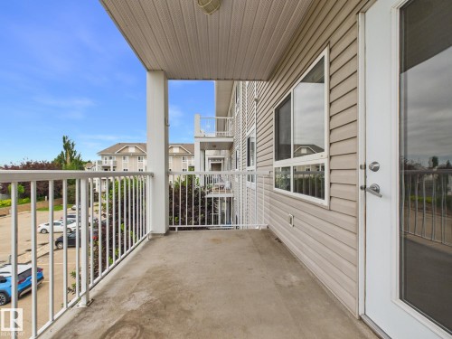 Private outdoor balcony featuring a concrete floor, white metal railing, and a light-colored siding exterior - #309 5350 199 St Nw, Edmonton, AB 