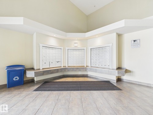 Main entrance featuring tiled flooring, a built-in mail center with three banks of mailboxes, and recessed lighting - #309 5350 199 St Nw, Edmonton, AB 