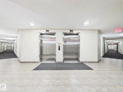 Dual stainless steel elevators framed by neutral walls and light-toned tile flooring - 