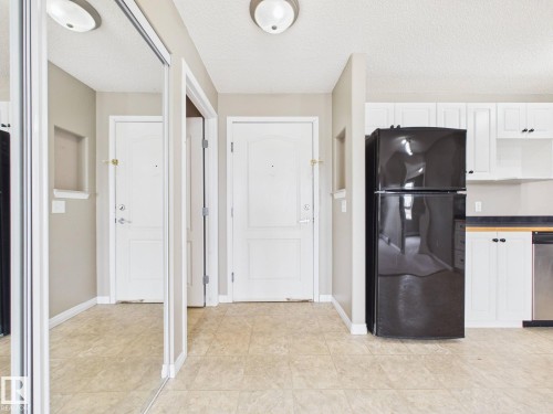 Entryway featuring light-toned flooring, white doors, and mirrored closet doors - #309 5350 199 St Nw, Edmonton, AB 