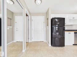 Entryway featuring light-toned flooring, white doors, and mirrored closet doors - 
