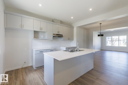 Modern kitchen featuring light gray cabinetry, white subway tile backsplash, and wood-finish flooring - 3619 Triomphe Boulevard, Beaumont, AB - Indoor Photo Showing Kitchen With Double Sink