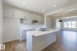 Modern kitchen featuring light gray cabinetry, white subway tile backsplash, and wood-finish flooring - 