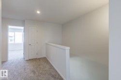 Carpeted hallway with a modern interior door, recessed lighting, and a partial wall with a white cap - 