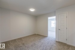 Neutral tone wall paint, textured carpeting, recessed ceiling lighting, a modern paneled door, and white trim - 