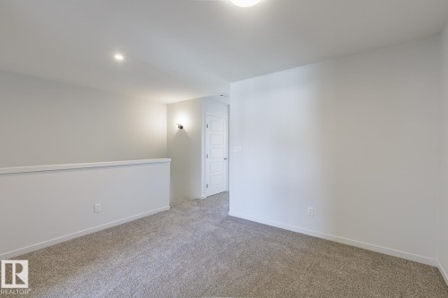 Carpeted loft area featuring a white railing, recessed ceiling lighting, and a white paneled door - 3619 Triomphe Boulevard, Beaumont, AB - Indoor Photo Showing Other Room