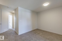Carpeted room with white walls, a flush-mount ceiling light fixture, and a white interior door with panel detailing - 