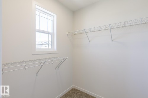 Walk-in closet featuring a double-hung window, white trim, wire shelving, and carpet flooring - 3619 Triomphe Boulevard, Beaumont, AB - Indoor With Storage