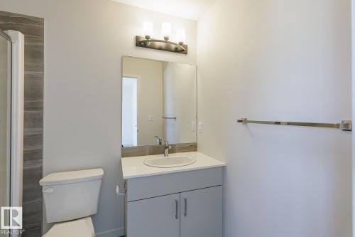 Bathroom vanity featuring a white countertop, undermount sink, and chrome faucet - 3619 Triomphe Boulevard, Beaumont, AB - Indoor Photo Showing Bathroom