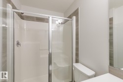 Bathroom featuring a glass-enclosed shower with a built-in seat, chrome fixtures, and a white shower surround - 